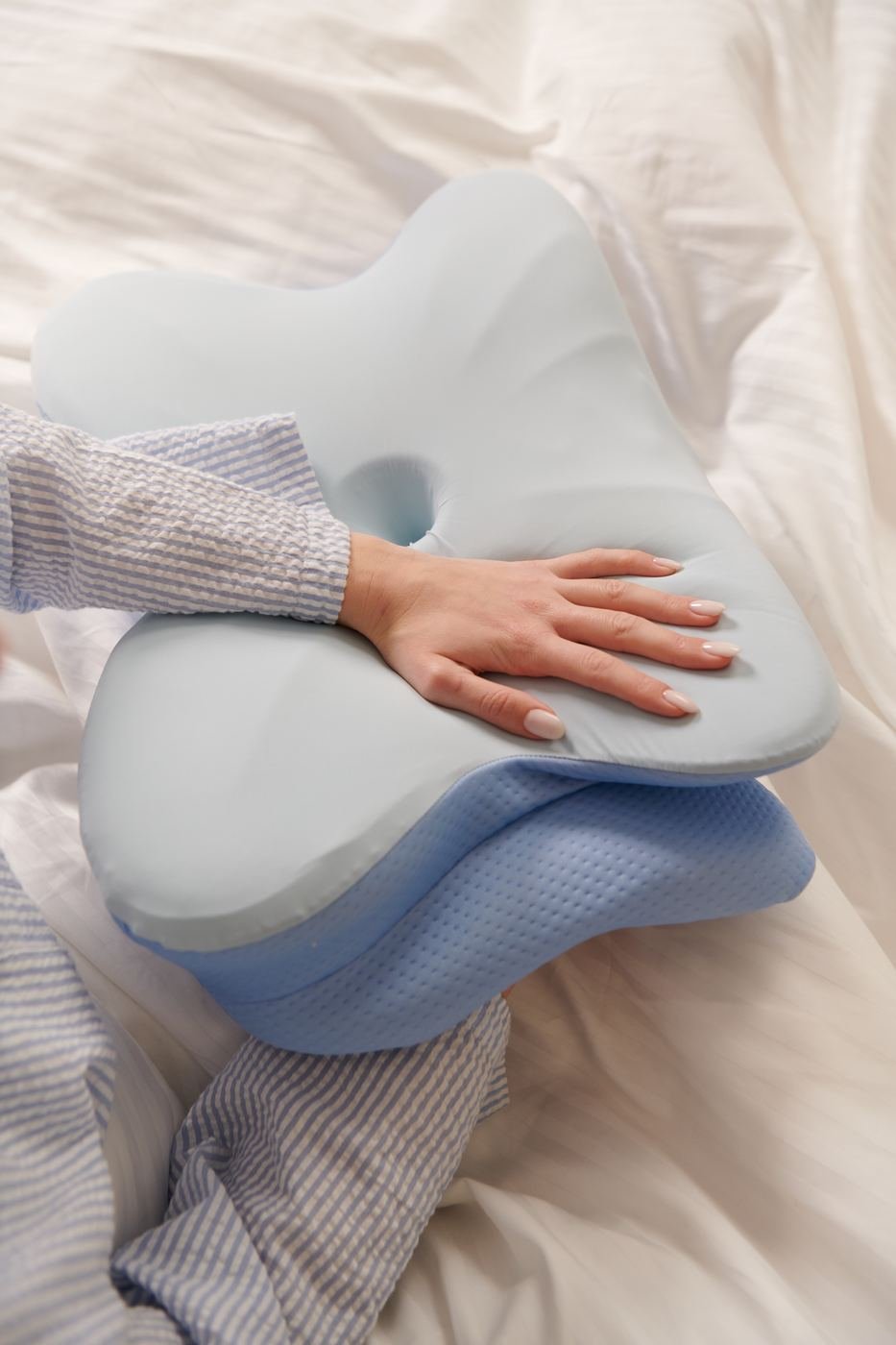 Close-up of a hand resting on the ergonomic pillow, showing the contoured chin-support cutout