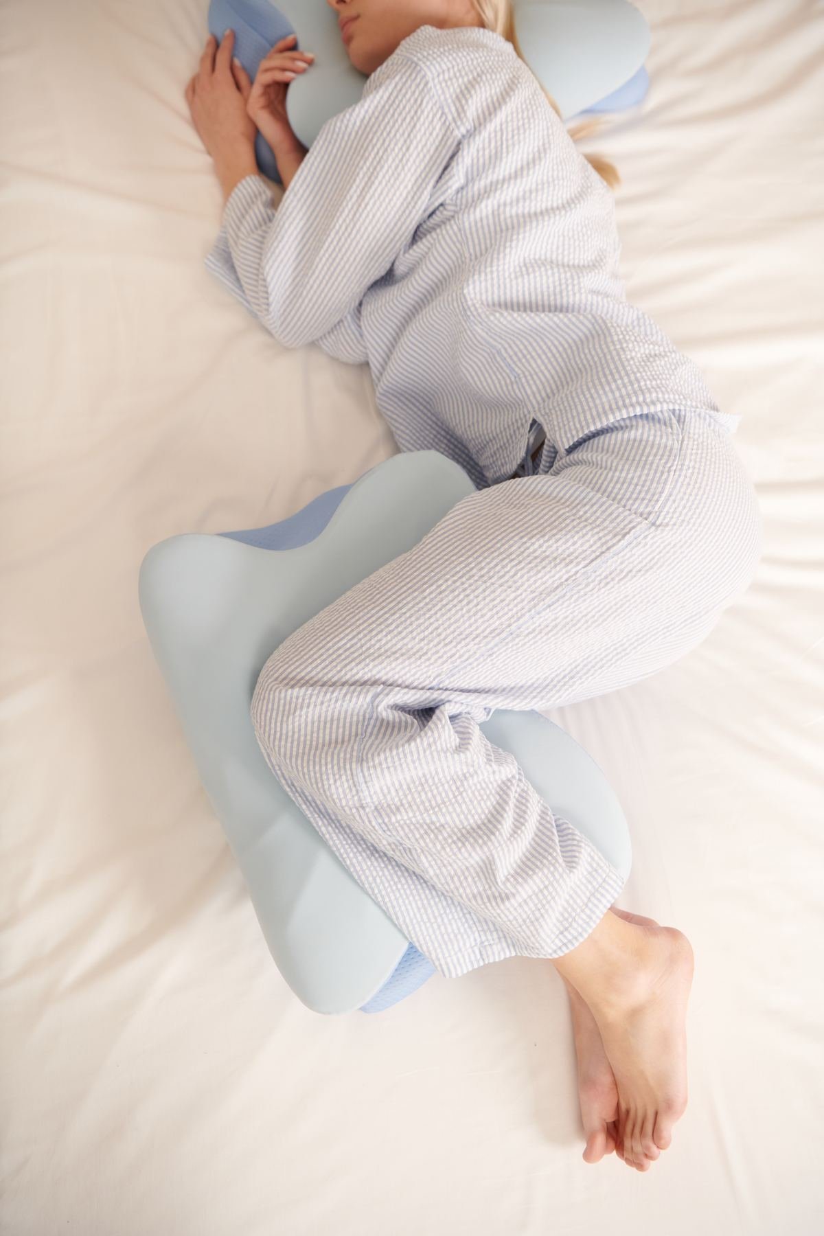 Woman sleeping on her side with her arm resting over the butterfly-shaped ergonomic pillow
